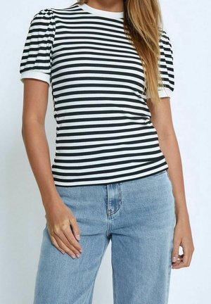 Czarnobiały top w paski z krótkim rękawem o prążkowanej fakturze i bufkami, zestawiony z jasnoniebieskimi dżinsami.