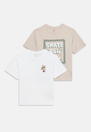 Due t-shirt a maniche corte: beige con la scritta "Skate" e grafica di uno skateboard, bianca con una piccola fetta di pizza in stile cartone animato che indossa scarpe da ginnastica e fa il segno della pace.