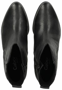 Bottines en cuir noir avec un bout pointu, des fermetures éclair latérales et une texture lisse. Logo de la marque visible à l'intérieur.