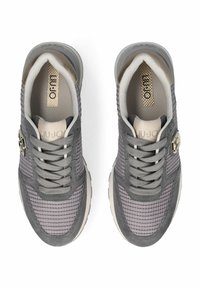 Un paio di sneakers grigie in rete e suede con lacci e dettagli in logo metallico, viste dall'alto su uno sfondo bianco.