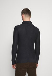 Maglione a collo alto blu navy con lavorazione a trama, polsini e orlo a coste. Presenta un design aderente per una silhouette snella.