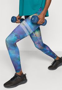 Πολύχρωμο κολάν με λουλουδάτο μοτίβο σε αποχρώσεις μπλε, μωβ και πράσινου. Διαθέτει υφή στη ζώνη μέσης και τρεις οριζόντιες ρίγες.