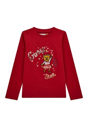 Camiseta roja de manga larga con un oso que lleva una falda, texto "Guess Star", estrellas, corazones y la frase "Pide un deseo y se hará realidad."