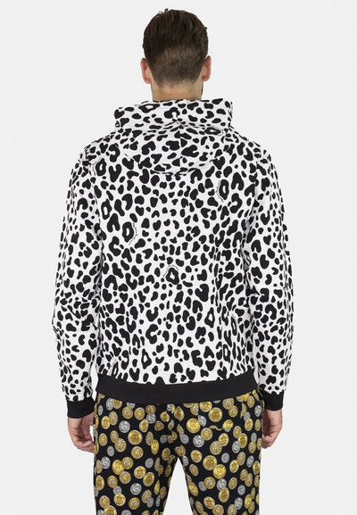 Felpa con motivo leopardato bianco e nero, dotata di cappuccio con cordino, abbinata a pantaloni neri con motivi circolari di monete d'oro e argento.