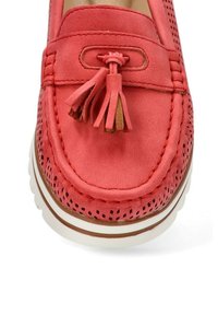 Zapato mocasín de cuero color coral con diseño perforado, acento de borlas y suela de goma blanca. Presenta ribetes en un tono marrón contrastante.