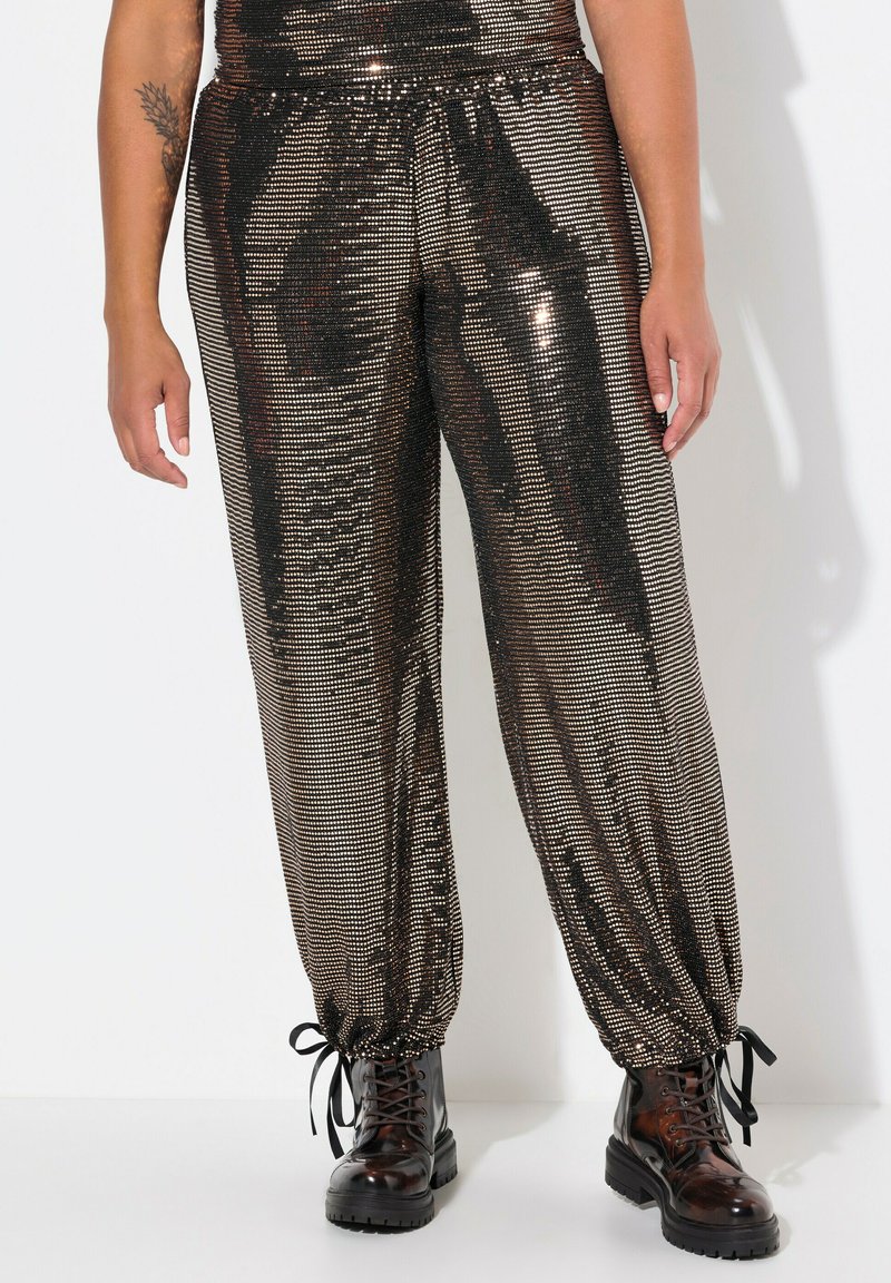 Zwarte en bronzen pailletten joggerbroeken met een relaxte pasvorm, trekkoordmanchetten en een glanzend metallic oppervlak. Gecombineerd met zwarte veterschoenen.
