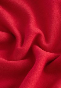 Jasně červená látka s měkkou, pletenou texturou, která má hladké vlny a konzistentní vzor tkaní po celé ploše.