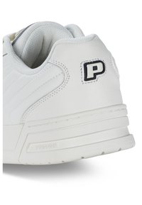 Fehér sneaker strukturált bőr külsővel, vízszintes varrással, párnázott bokarésszel és fekete logóval a saroknál.