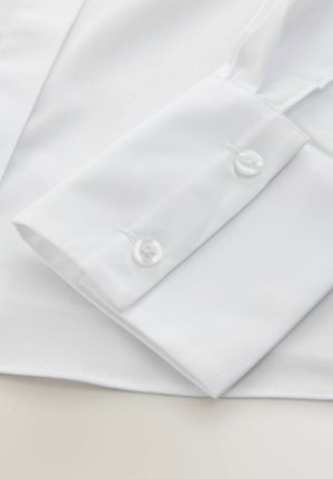 Copa de camisa blanca con dos botones redondos blancos, tejido de algodón, textura suave y costura limpia a lo largo de los bordes.