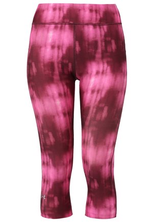 Frau läuft in schwarzem ärmellosem Sporttop, pinkfarbenen Batik-Capri-Leggings und schwarzen Laufschuhen vor einfarbigem Hintergrund.