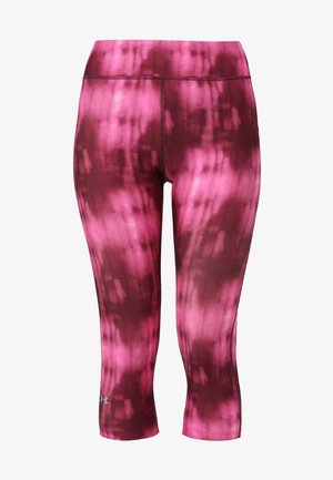 Frau läuft in schwarzem ärmellosem Sporttop, pinkfarbenen Batik-Capri-Leggings und schwarzen Laufschuhen vor einfarbigem Hintergrund.