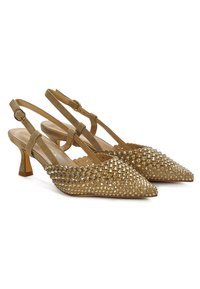 Zapatos de tacón slingback dorados con punta afilada, decorados con tachuelas. Presentan un bajo tacón bloque y un diseño recortado en los lados.