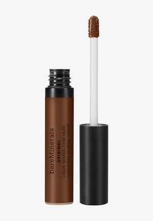 Flydende mineralconcealer i en brun cylindrisk tube med sort låg. Indeholder en hvid applikatorstav og en fed sort tekstetiket.