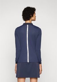 Námornícky polokošeľ s dlhým rukávom a golierom, so štýlovou bielou vertikálnou logovou páskou na chrbte a voľným strihom, ideálny na neformálne nosenie.