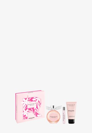 Coffret cadeau rose avec boîte décorée de fleurs, flacon de parfum rond avec ruban, petit spray et tube de lotion pour le corps par Mademoiselle Rochas.