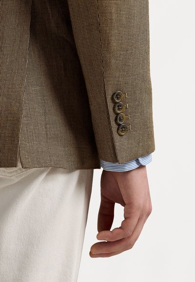 Bruine geblokte blazer met een slim fit, vier knopen bij de mouw en een zichtbare blauwe en witte gestreepte mouw van een shirt eronder.