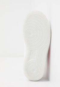 Vitt sneakersula med cirkulära och vågiga mönster. Tillverkad av gummi, med en logotypstämpling nära hälen och slät yta.