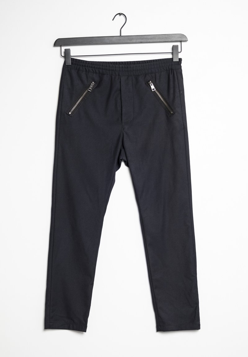 Svarta byxor med elastisk midja, två fickor med dragkedja framtill, slim fit och en jämn tygtextur.