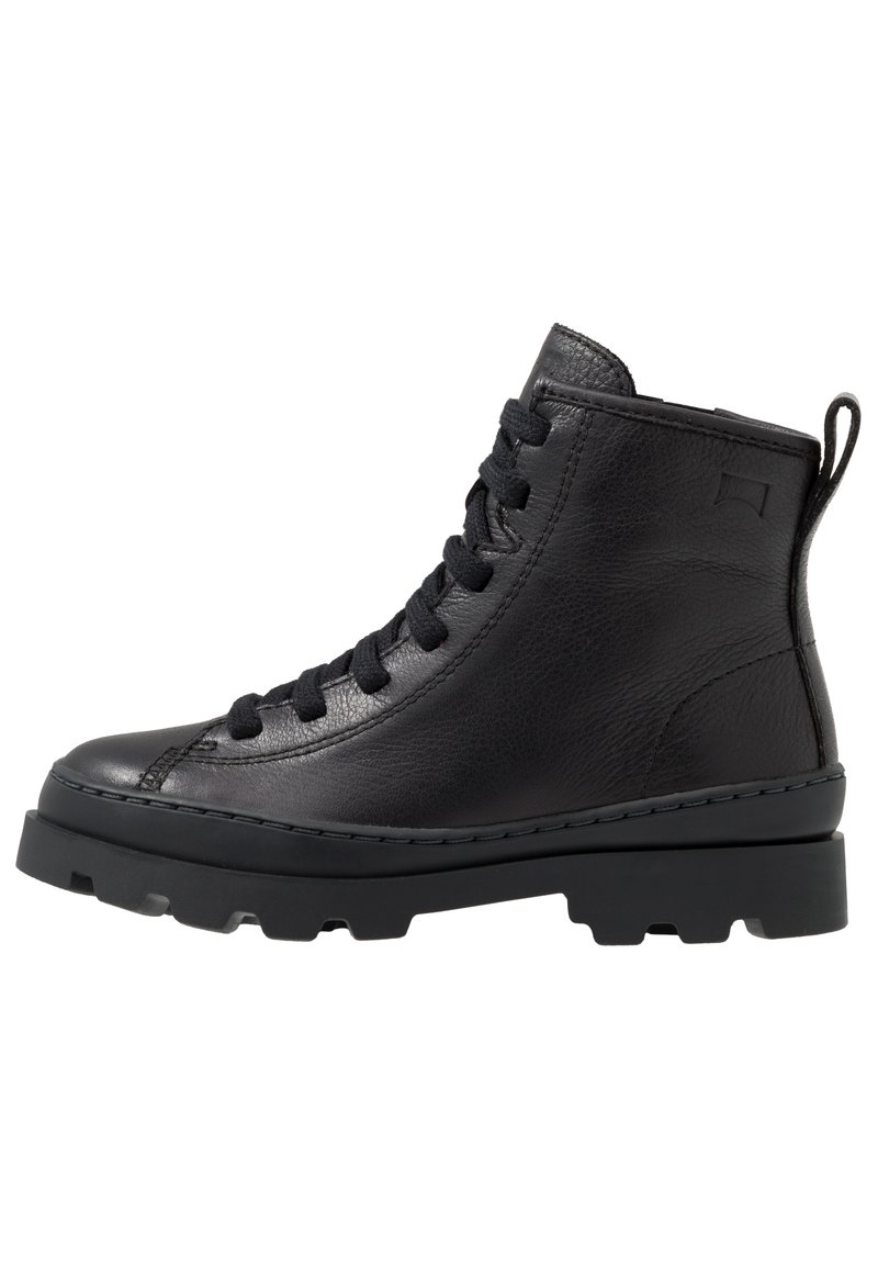 Bottine en cuir noir avec bout rond, devant à lacets, tige texturée et semelle en caoutchouc chunky. Dispose d'une languette à l'arrière.