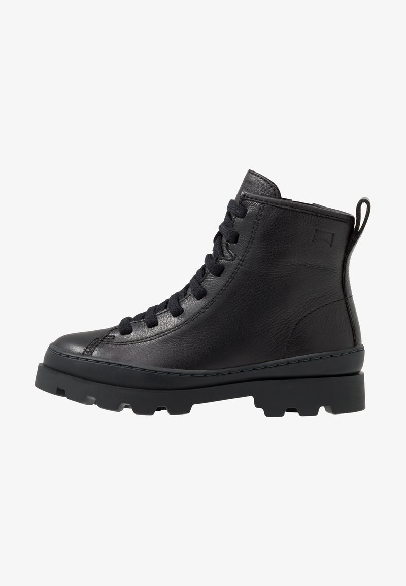 Bottine en cuir noir avec bout rond, devant à lacets, tige texturée et semelle en caoutchouc chunky. Dispose d'une languette à l'arrière.