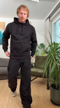 Sweatshirt preta com capuz, bolso frontal e cordão, combinada com calças largas pretas de veludo cotelê. Textura macia, design minimalista e corte casual.