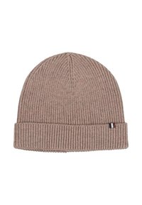 Beige ribbed knit beanie hat with folded brim and small rectangular tag featuring blue, white, and brown stripes on the front side.