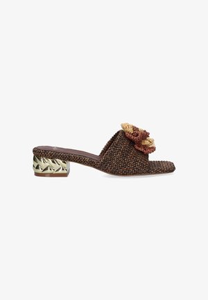 Sandalia mule marrón tejida con puntera cuadrada, flor trenzada decorativa en beige y marrón en la parte superior y tacón bajo en bloque metálico dorado esculpido.