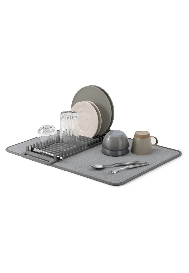 Grau gefärbte Abtropfmatte mit verschiedenen Küchenutensilien: ein klares Glas, zwei Tassen, graue Teller und metallisches Besteck, angeordnet auf einem gerippten Abtropfgitter.