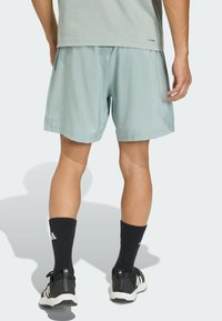 Pantalones cortos deportivos azul claro con cintura elástica, textura suave y bolsillos laterales. Se llevan con calcetines negros y zapatillas deportivas.