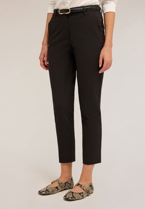 Zwarte, op maat gemaakte broeken met een slim fit, voorzien van een rits en zijzakken. Gecombineerd met zwarte en tan slangenprint ballerina's.
