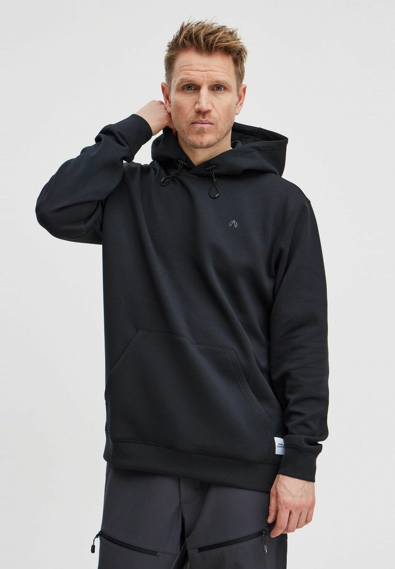 Svart hoodie gjord av mjukt, tjockt material med en framficka, dragsko i huvan och diskret logodetalj på bröstet.