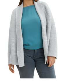 Cardigan lavorato a maglia grigio chiaro con apertura frontale e maniche larghe, indossato sopra una blusa verde petrolio. Abbinato a jeans scuri.