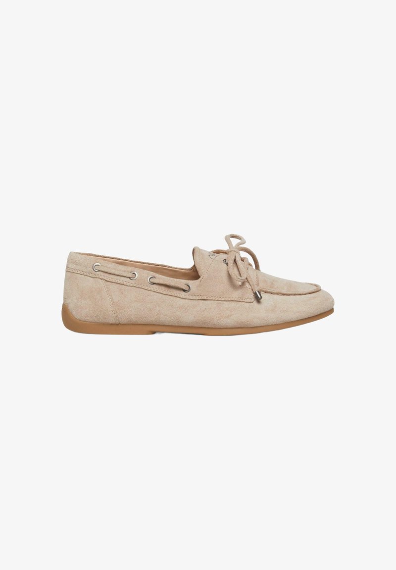 Mocassin en daim beige avec détail de lacet en nœud, œillets latéraux et semelle en caoutchouc marron plate, vu de côté extérieur.