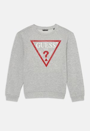 Sudadera gris de mangas largas, con puños acanalados, que presenta un logo triangular rojo con "GUESS® U.S.A." y un signo de interrogación en el centro.