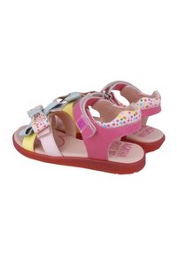 Sandalias infantiles coloridas que presentan una mezcla de materiales en rosa, amarillo y azul, un acento de lazo y suelas de goma texturizadas.
