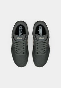 Gray sneakers made of suede with a smooth finish, featuring flat laces, perforations, and an "etnies" logo on the tongue.