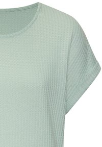 Svetlozelené, textúrované tričko s krátkymi rukávmi a zaobleným výstrihom. Tkanina má rebrový vzor.