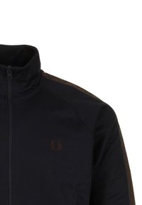 Giacca nera con zip e colletto alto, con logo di alloro marrone sul petto, caratterizzata da dettagli a strisce marroni sulla spalla e sulla manica.