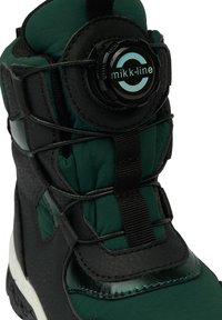 Musta ja vihreä talvijääkähmä with pehmustetulla varrella, teksturoidulla mustalla materiaalilla, pyöreällä sulkimella ja vahvistetulla kärjellä kestävyyden takaamiseksi.