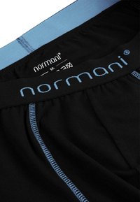 Black cotton boxer shorts with light blue elastic waistband, featuring contrasting blue stitching and the brand name "normani" on the waistband.