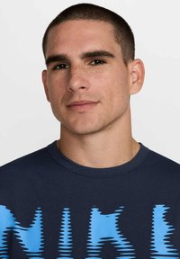 Navy t-shirt featuring a blue graphic print with a wavy pattern. Short sleeves and a crew neck design. Smooth fabric texture.