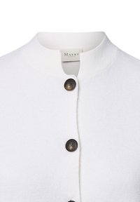 Cardigan bianco lavorato a maglia con scollatura rotonda, cinque bottoni scuri e una texture morbida. Etichetta visibile sul collo.