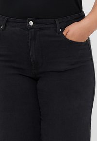 Black denim jeans with a high waist, front pocket, and silver button detail. Smooth texture, fitted design, and straight-leg cut.
