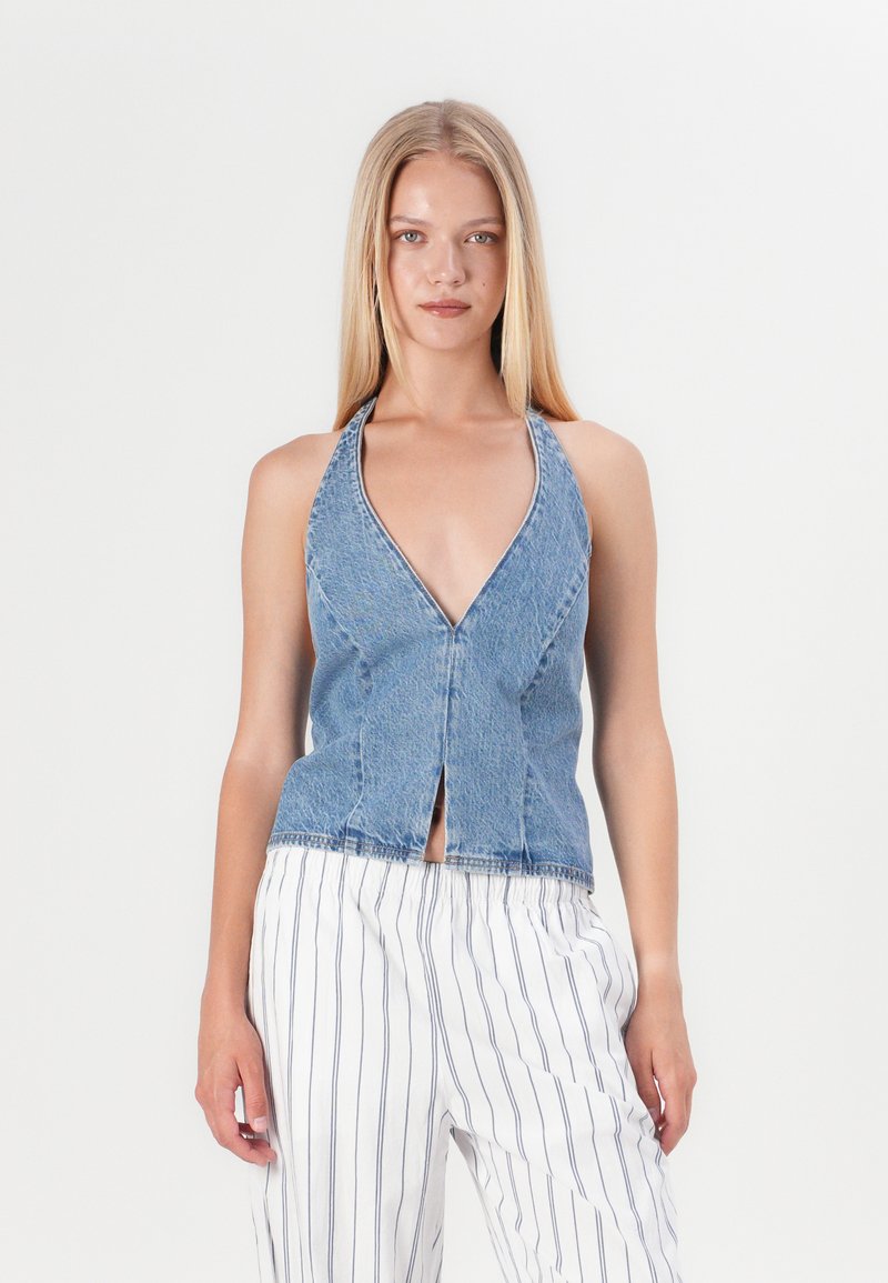 Jeans halterneck-topp med djup V-krage, framöppning och åtsittande design. Ljusblå färg, något blekt textur och minimal sömdetalj.
