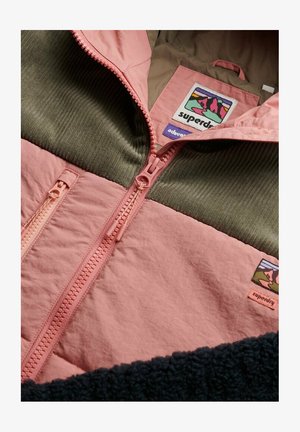 Chaqueta de cremallera rosa y verde con tela texturizada, una sección de pana y etiqueta de marca con un diseño de montaña.