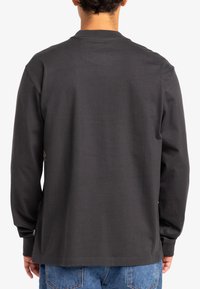 Grijze langekatoen shirt met lange mouwen, ronde hals en een relaxte pasvorm. Gemaakt van zachte katoen en heeft een klein logo detail op de linker mouw.