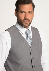 Chaleco gris sobre camisa blanca, con una textura sutil, cinco botones y una corbata de rayas azul claro con diseños intrincados.