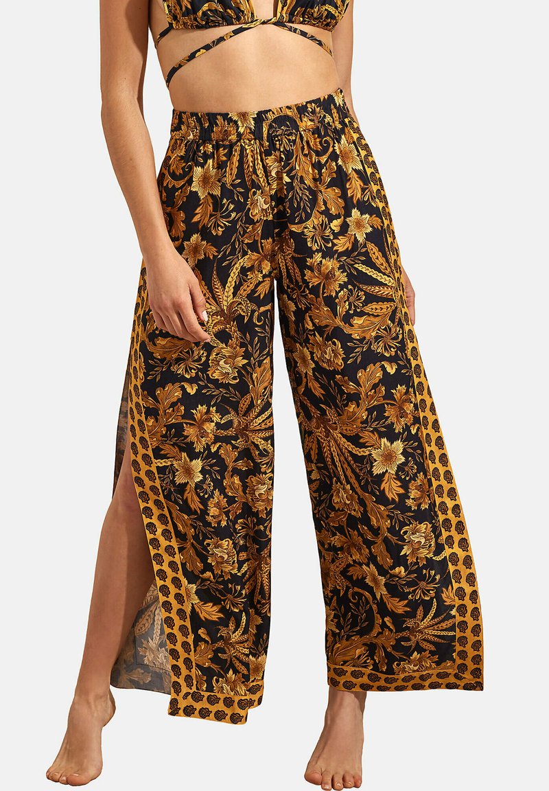 Pantalons larges à fleurs noires avec des accents dorés. Présente un motif floral, une taille élastique et des fentes latérales pour le confort et le style.