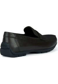 Brązowe skórzane buty wsuwane z przeszyciami i gumową podeszwą z otworami drenażowymi, zaprojektowane z myślą o wentylacji i komforcie.