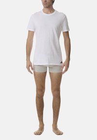 White crew-neck t-shirt made of cotton with short sleeves; paired with light grey boxer shorts. Minimal branding on shorts.